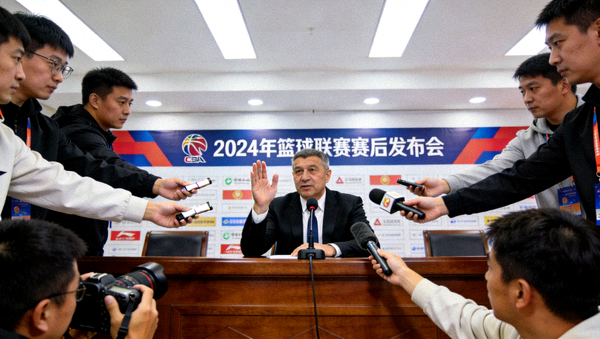 体育赛后新闻发布会现场，教练正在回答记者提问